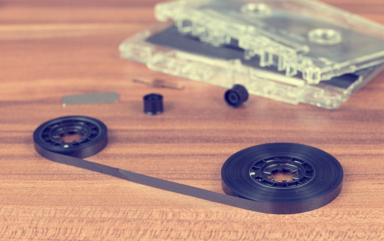 Disassembled cassette parts on wooden table create a vintage tech aesthetic.